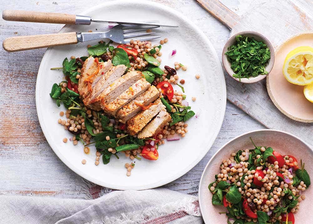 A knife and fork on a white plate with salad and meat